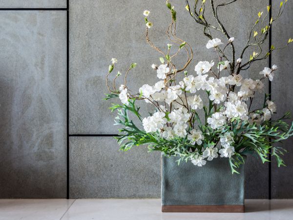 دیوار داخلی خالی مدرن با گل های مصنوعی در گلدان سرامیکی