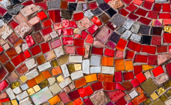قطعات رنگارنگ شیشه و سنگ با فشار دادن به سنگ تراشی طرحی تزئینی و رنگارنگ موزاییکی را ایجاد می کند