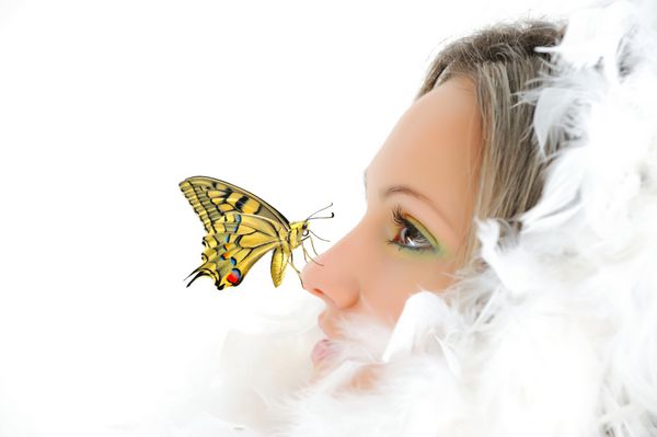 دختر زیبا با پرهای سفید و پروانه رنگارنگ روی بینی اش