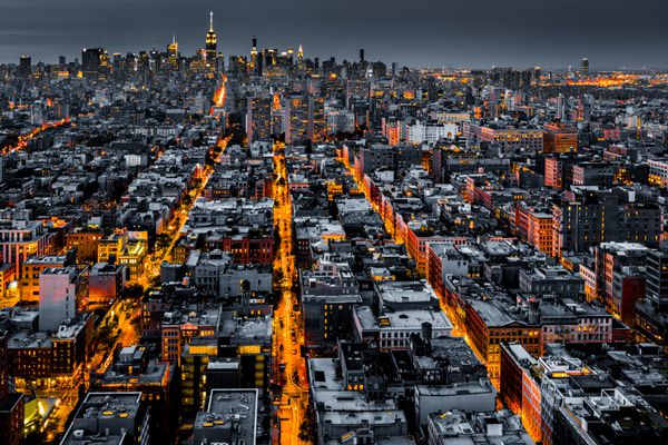 نمای هوایی از شهر نیویورک در شب با خیابان های نورانی که به سمت مرکز شهر همگرا می شوند