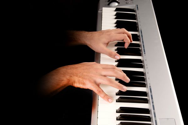 مرد جوان خوش تیپ پیانوی جدا شده در پس زمینه تاریک