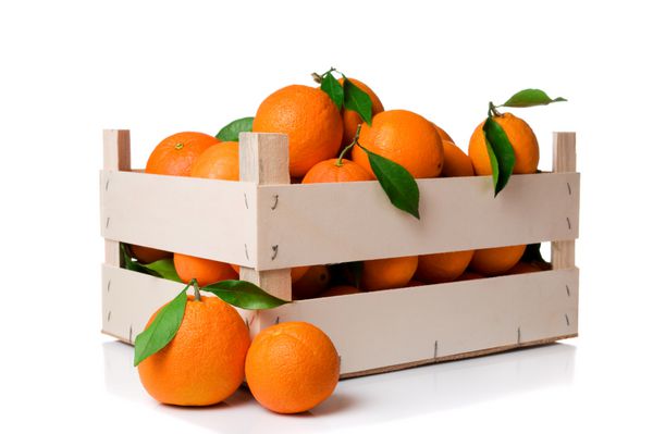 میوه های نارنجی تازه و رسیده با برگ هایی در یک جعبه چوبی جدا شده در پس زمینه سفید