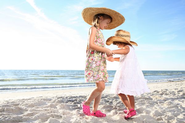 دو دختر کوچک در ساحل آفتابی می رقصند در مقابل خورشید شلیک کنید