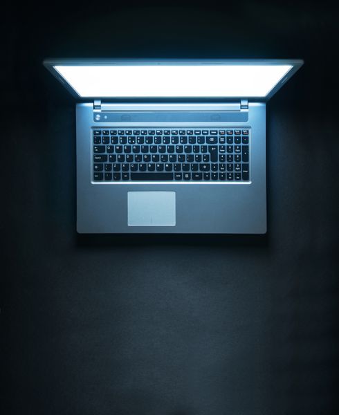 لپ تاپ با صفحه نمایشی که در تاریکی می درخشد