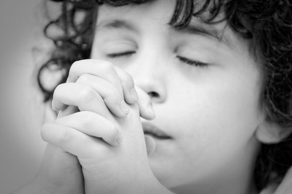 کودک خردسالی که در طول رابطه عبادی روزانه و پسر مسیحی خود با عیسی به شدت و با احترام به خدا دعا می کند تصویر سیاه و سفید