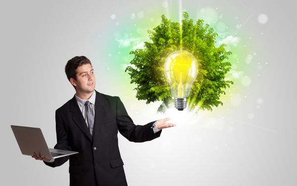 مرد جوان در حال ارائه لامپ ایده با مفهوم درخت سبز