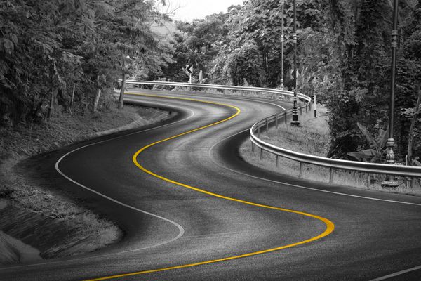 مسیر منحنی سیاه و سفید جاده آسفالته در طبیعت با خط زرد