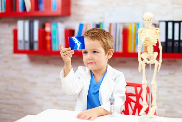 بچه ناز یک دکتر به تصویر اشعه ایکس از پا نگاه می کند