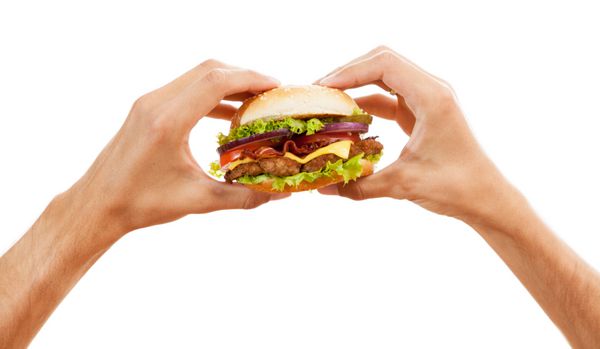 دست هایی که یک همبرگر را در دست دارند جدا شده در پس زمینه سفید