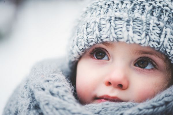 پرتره زمستانی نزدیک در فضای باز از دختر بچه رویایی شایان ستایش با کلاه بافتنی خاکستری و شال گردن