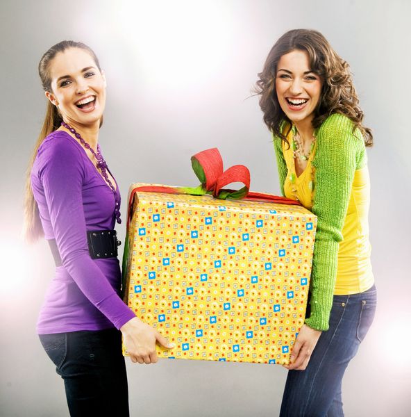پرتره دو دختر زیبای شاد که یک هدیه در دست دارند