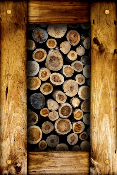 تصویر انتزاعی از کنده های هیزم برش خشک در یک توده در داخل یک قاب چوبی