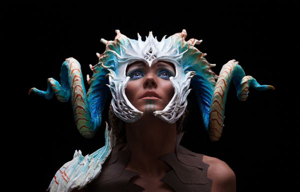 مفهوم فانتزی دختری جوان جنگجوی قوی شجاع عضلانی با کلاه ایمنی - ماسک با شاخ روی سر با رنگ سفید مرجانی با نقطه و مشاهده الگوهای موجودات