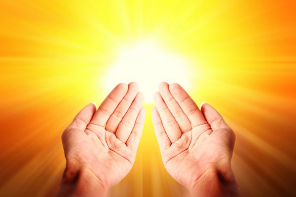 تصویر دینی اسلامی نمای نزدیک از دست‌های باز روی پس‌زمینه نور روشن زرد دعا کنید