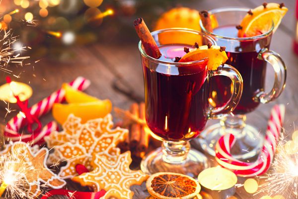 مولد نوشیدنی سنتی کریسمس با چوب دارچین تکه‌های پرتقال و ادویه جات در میز کریسمس تزئین شده در تعطیلات شام کریسمس