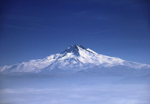 منظره مه آلود خارق العاده کوه erciyes - یک آتشفشان باستانی در پس زمینه آسمان آبی منظره دور از روستای اوچیسار در نزدیکی گورمه کاپادوکیه آناتولی مرکزی ترکیه