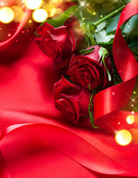 پس زمینه هدیه دسته گل رز قرمز روز بر روی پس زمینه ابریشم هدیه عروسی یا هدیه طراحی هنری با دسته گل های زیبا و نزدیک روبان ساتن قرمز