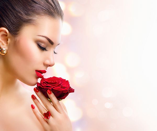 زن زیبایی با گل رز قرمز مدل مد دختر پرتره با گل رز قرمز در دست لب و ناخن قرمز آرایش و مانیکور لاکچری زیبا
