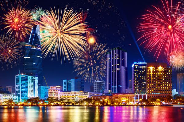جشن خط افق با آتش بازی آسمان را بر فراز منطقه تجاری در شهر هو چی مین سایگون ویتنام روشن می کند منظره زیبای شهر در شب تعطیلات جشن سال نو
