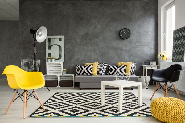 اتاق نشیمن خاکستری با مبل صندلی چراغ ایستاده میز کوچک جزئیات زرد و تزئینات الگوی سیاه و سفید