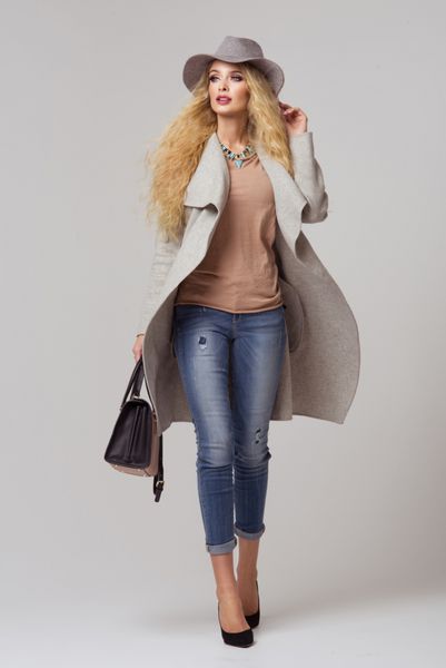 مدل بلوند مد با لباس های زیبا که در استودیو ژست می گیرد پوشیدن کت کلاه کیف دستی شلوار جین پاره