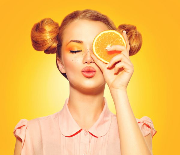 دختر مدل زیبایی پرتقال های آبدار می گیرد دختر نوجوان شاد و زیبا با کک و مک مدل موی قرمز خنده دار و آرایش زرد آرایش حرفه ای برش پرتقال