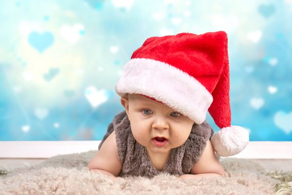 کریسمس کودکی کودکی و مفهوم مردم - کودک شاد با کلاه بابا نوئل در پس زمینه قلب تعطیلات