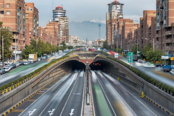تهران ایران - 26 اکتبر 2016 جریان ترافیک در داخل خارج و اطراف تونل توحید با پس زمینه برج میلاد و کوه های البرز این سومین تونل طولانی شهری در خاورمیانه است