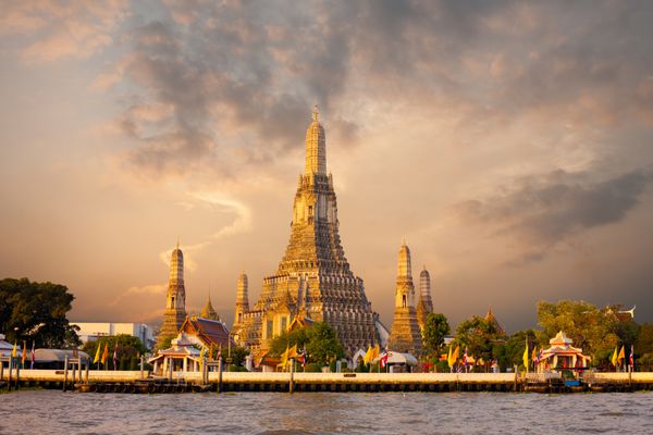 معبد نمادین سپیده دم وات آرون در امتداد رودخانه چائو فرایا با آسمان قرمز رنگارنگ در طلوع صبح در بانکوک تایلند