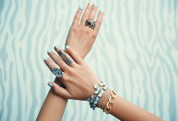 دست های زن با جواهرات در پس زمینه رنگی