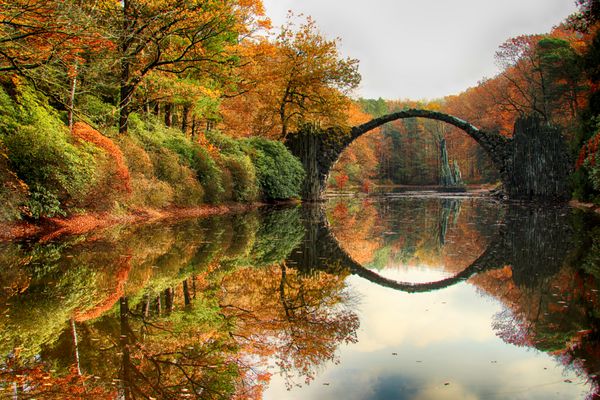 پل راکوتز rakotzbrucke پل شیطان در کروملائو زاکسن آلمان پاییز رنگارنگ انعکاس پل در آب یک دایره کامل ایجاد می کند