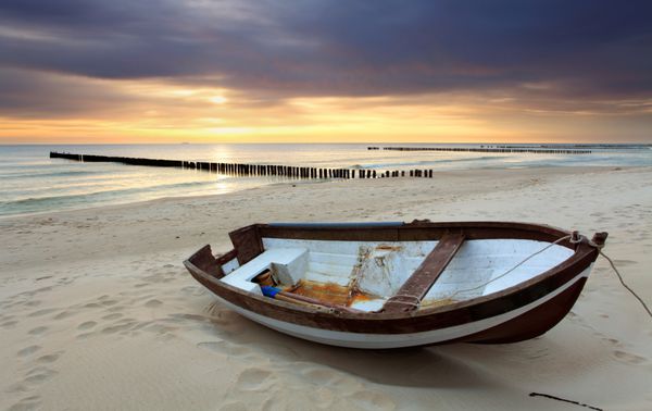 قایق در ساحل زیبا در طلوع آفتاب