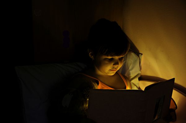 دختری که با لامپ کتاب می خواند