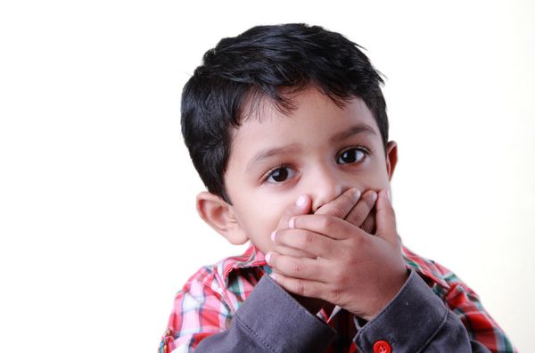 پسر کوچکی که با پوشاندن دست های دهانش سکوت می کند