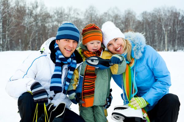 والدین جوان خوشحال با پسرشان به اسکیت روی یخ می روند