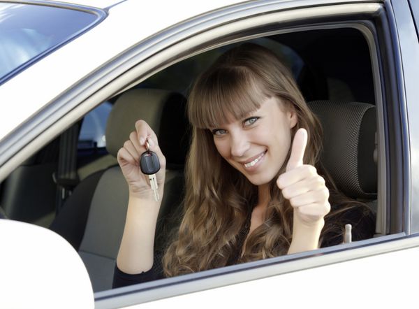 زن جوان شاد و زیبا با کلید ماشین