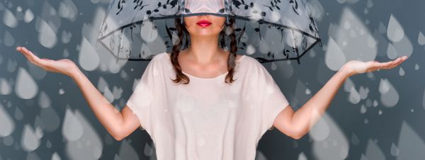 پرتره زن جوان شیک پوش زیبا که زیر چتر ایستاده و قطرات آب جعلی باران را می گیرد مفهوم ایمنی