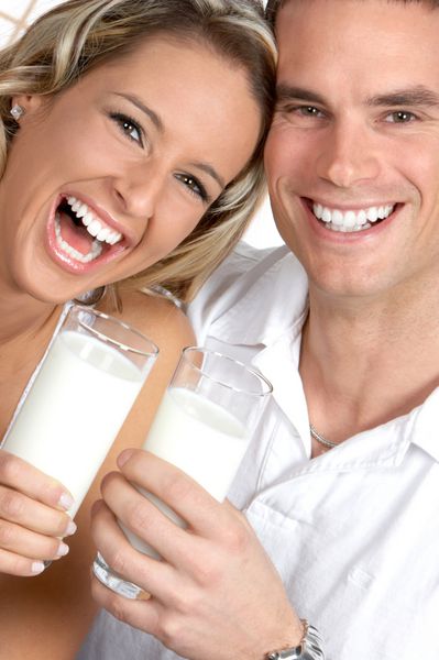 زوج عاشق جوان در حال نوشیدن شیر روی پس زمینه سفید