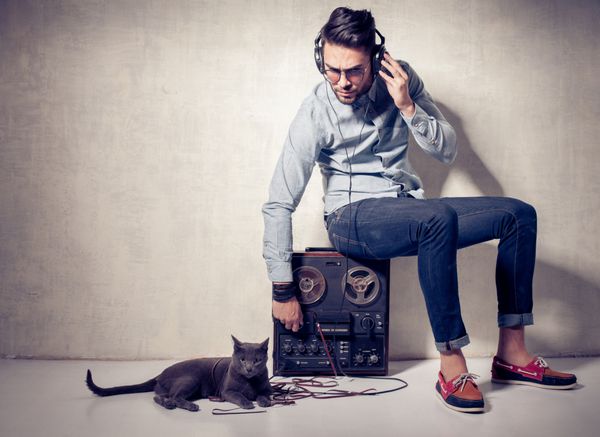 مرد خوش تیپ و گربه در حال گوش دادن به موسیقی با مگنتوفون