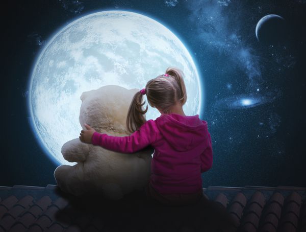 دختر ناز کوچکی که با خرس اسباب بازی نشسته است