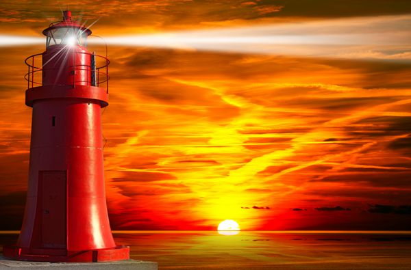 فانوس دریایی قرمز با پرتو نور در غروب خورشید