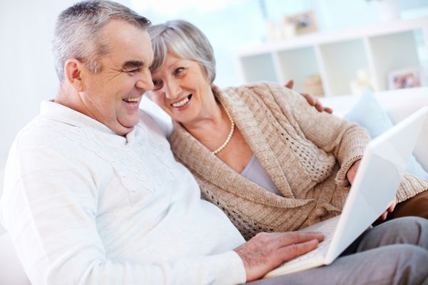 پرتره مرد بالغ و همسرش که با لپ تاپ در خانه کار می کنند