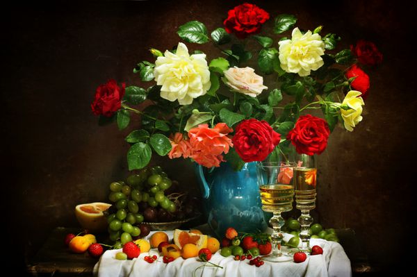دسته گلی درخشان و باشکوه از قرمز و زرد هر دو گل رز صورتی و سفید معطر در لیوان های غلیظ و میوه های رسیده آبدار