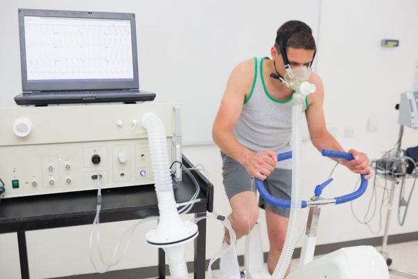 مردی در حال انجام تست تناسب اندام با دوچرخه ورزشی در مرکز پزشکی