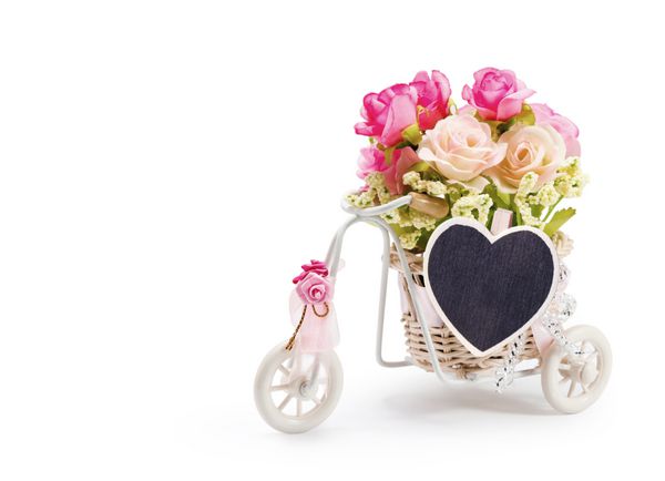 گل های رز در سبد دوچرخه با سنجاق لباس قلب در پس زمینه سفید
