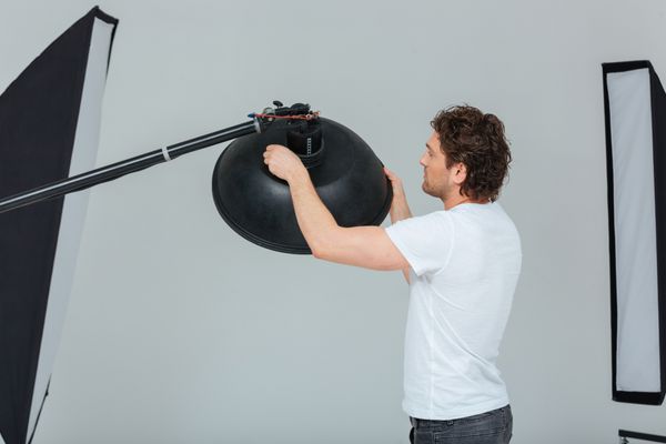 عکاس مرد در حال تهیه تجهیزات نورپردازی در استودیو