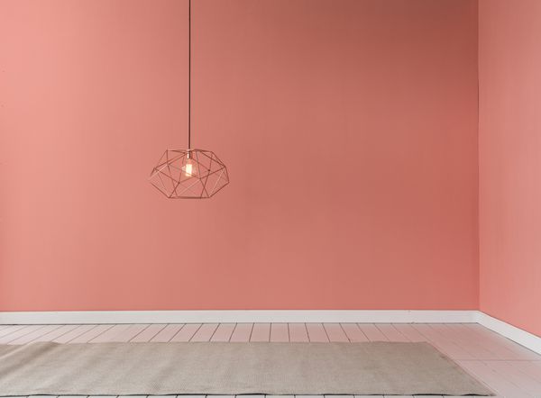 دیوار رنگ صورتی روشن با لامپ مدرن و مفهوم صندلی مشکی