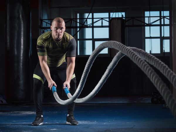 مردان با طناب نبرد در سالن بدنسازی ورزش می کنند کراس فیت
