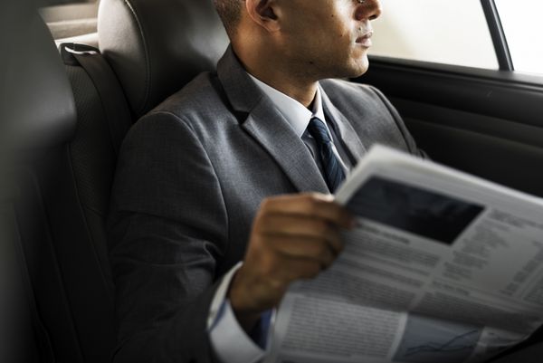 تاجر داخل ماشین نشسته به خواندن روزنامه