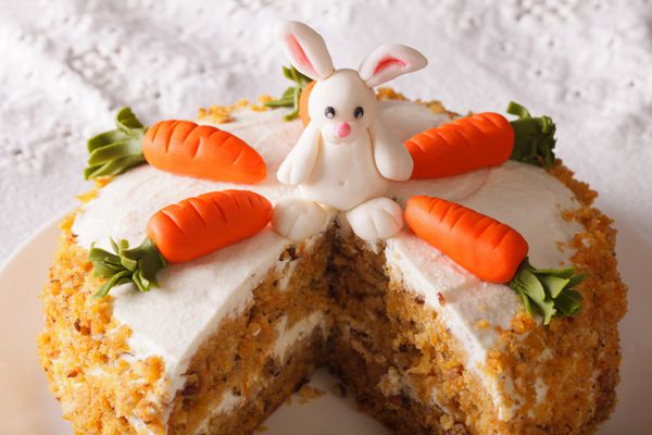 تکه ای از کیک هویج را که با نمای نزدیک خرگوش تزئین شده است ببرید افقی